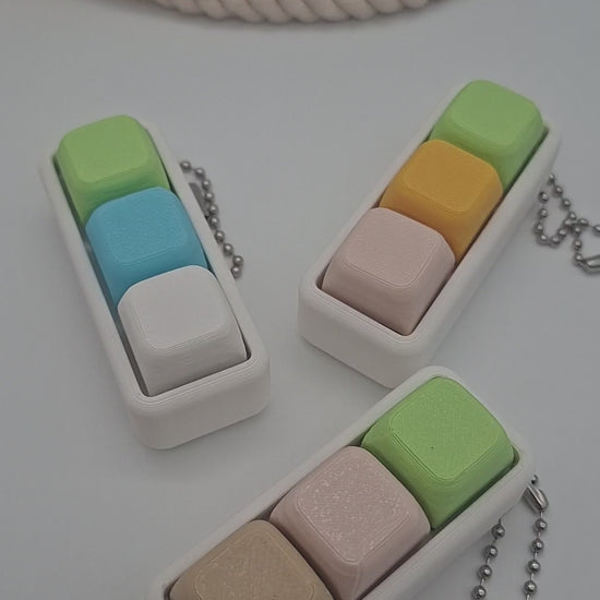 Pastellfarbener Keyboard Klicker mit drei Keycaps auf weißem Gehäuse als sensorisches Fidget für Konzentration und Entspannung.